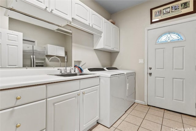 laundry area featuring washer and dryer, light tile patterned floors, cabinet space, and a sink