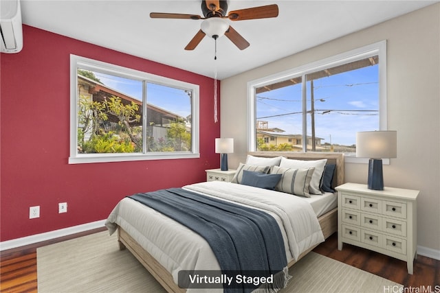 bedroom featuring baseboards, multiple windows, dark wood-style flooring, and a wall unit AC