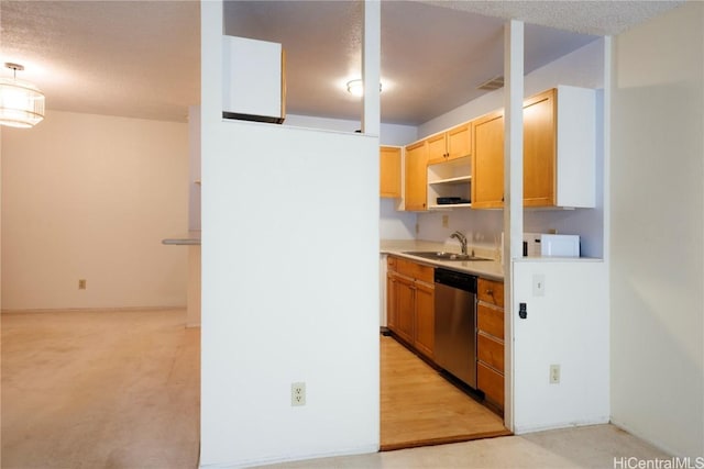 kitchen with stainless steel dishwasher, light brown cabinets, sink, and a textured ceiling