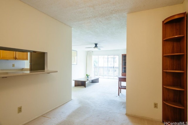 hallway with light carpet and a textured ceiling