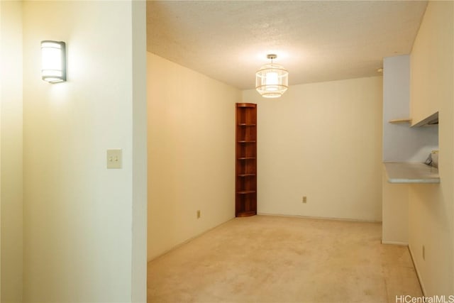 unfurnished dining area featuring light colored carpet and a textured ceiling