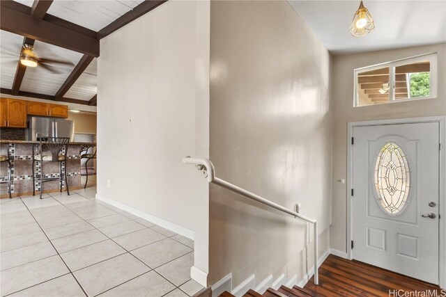 entryway featuring ceiling fan, light tile patterned floors, and lofted ceiling with beams