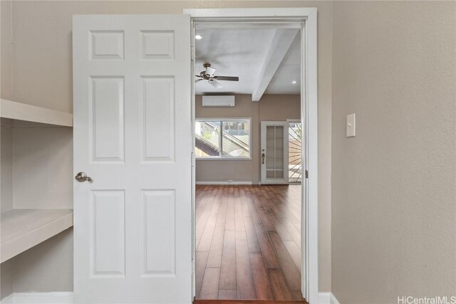 hallway featuring an AC wall unit, dark hardwood / wood-style flooring, and beamed ceiling