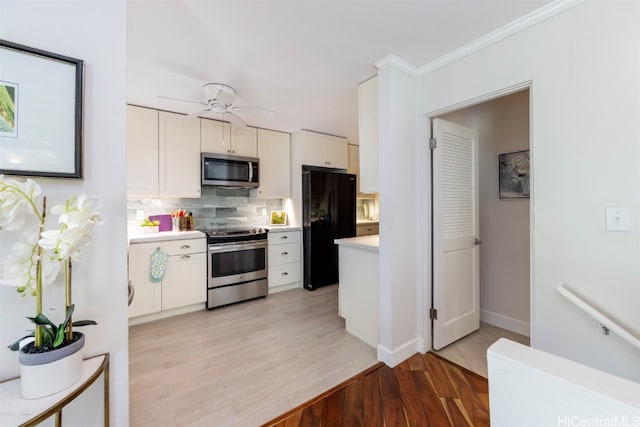 kitchen with backsplash, light hardwood / wood-style floors, stainless steel appliances, white cabinets, and crown molding