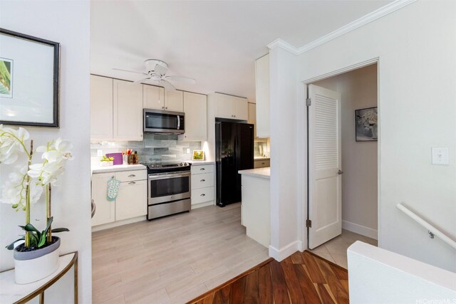 kitchen with backsplash, appliances with stainless steel finishes, light wood-type flooring, light countertops, and white cabinetry