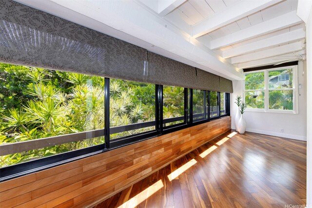 spare room with wood-type flooring, baseboards, and beam ceiling