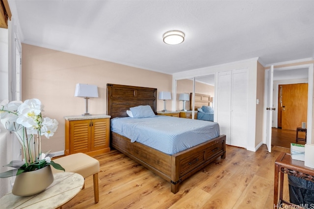 bedroom featuring light hardwood / wood-style flooring, a closet, and crown molding