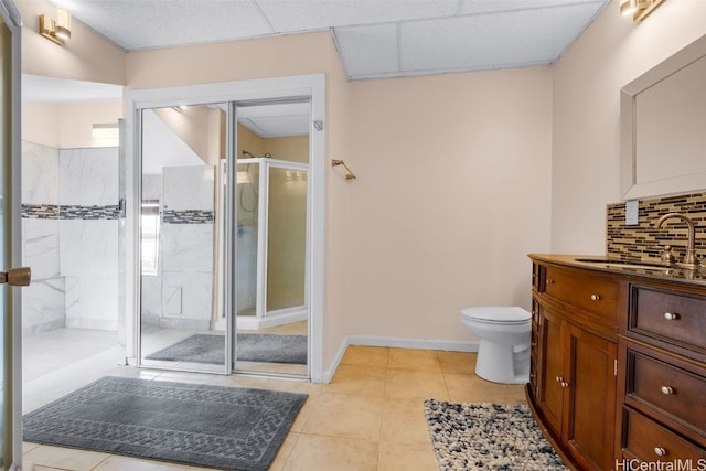 bathroom with decorative backsplash, toilet, vanity, an enclosed shower, and tile patterned flooring