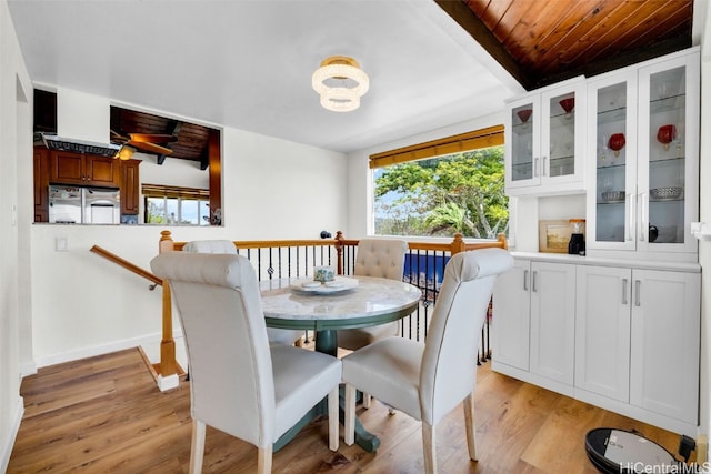 dining area featuring beamed ceiling, light hardwood / wood-style flooring, and wood ceiling