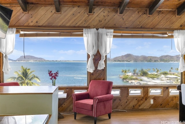 living area featuring beamed ceiling, light hardwood / wood-style floors, and a water and mountain view