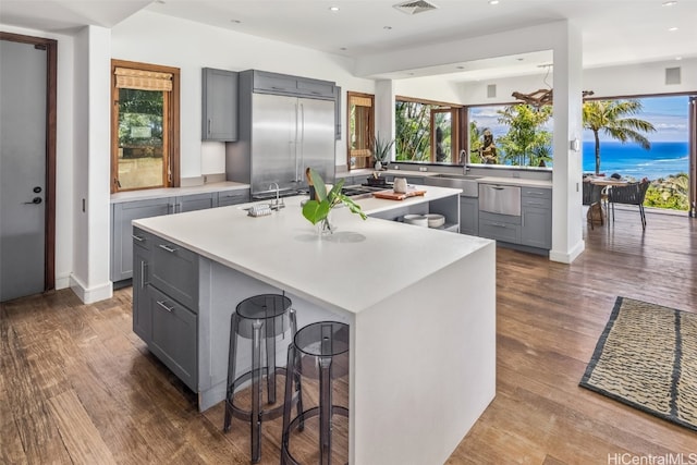 kitchen with a kitchen bar, dark hardwood / wood-style flooring, an island with sink, and gray cabinets