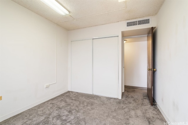 unfurnished bedroom featuring a closet, a textured ceiling, and light colored carpet