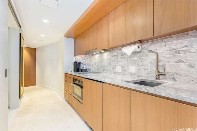 kitchen featuring stovetop, oven, sink, light stone counters, and tasteful backsplash