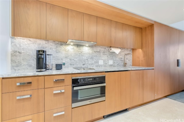 kitchen with light brown cabinets, decorative backsplash, stainless steel appliances, and light stone counters