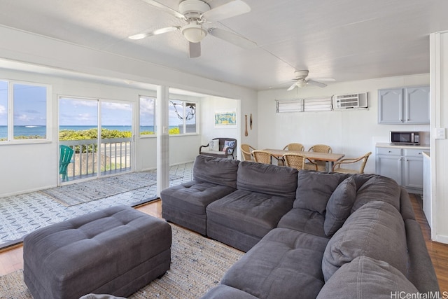 living room with a water view, ceiling fan, a wall mounted air conditioner, and hardwood / wood-style floors