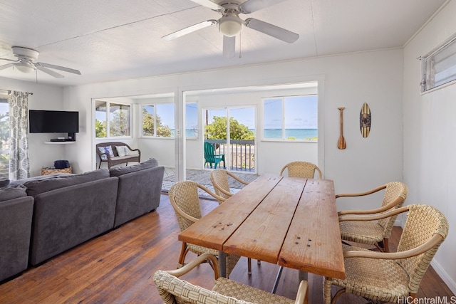 dining room with a water view, ceiling fan, a textured ceiling, and dark hardwood / wood-style flooring