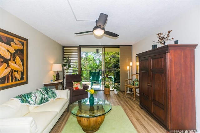 living room featuring a textured ceiling, a wall of windows, light hardwood / wood-style floors, and ceiling fan