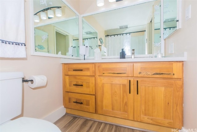 bathroom featuring vanity, hardwood / wood-style flooring, toilet, and walk in shower