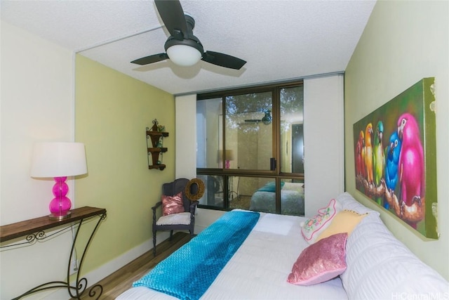 bedroom with hardwood / wood-style floors, a textured ceiling, a wall of windows, and ceiling fan