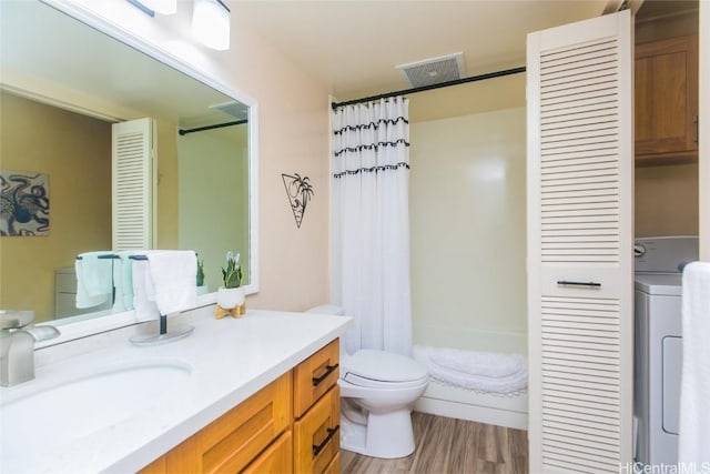 full bathroom featuring washer / dryer, hardwood / wood-style flooring, vanity, shower / tub combo, and toilet