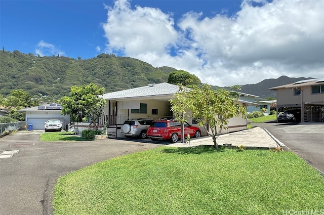 view of front of property with a front lawn, a mountain view, and a carport