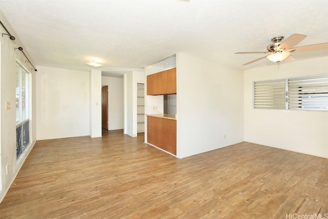 unfurnished living room featuring ceiling fan, a textured ceiling, light hardwood / wood-style flooring, and a barn door