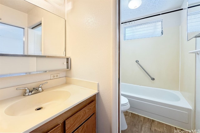 full bathroom featuring shower / bathing tub combination, hardwood / wood-style floors, a textured ceiling, toilet, and vanity