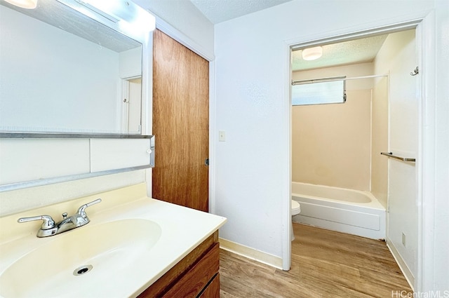 full bathroom featuring hardwood / wood-style floors, a textured ceiling, toilet, shower / bathtub combination, and vanity