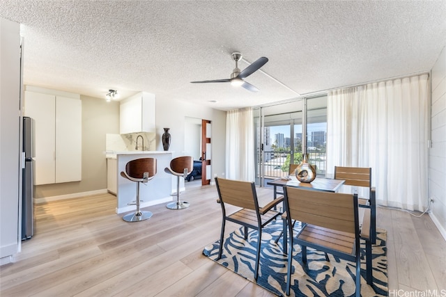 dining space featuring light hardwood / wood-style flooring, a textured ceiling, and ceiling fan