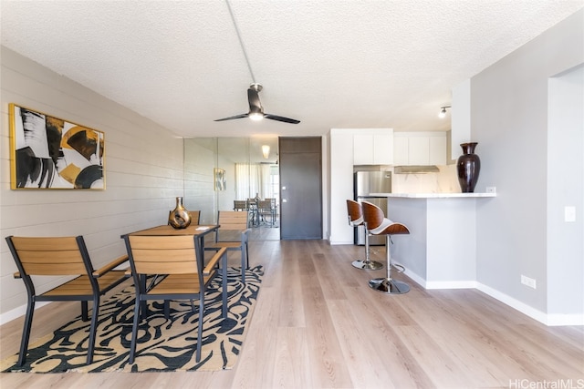 dining room with light hardwood / wood-style flooring, a textured ceiling, and ceiling fan