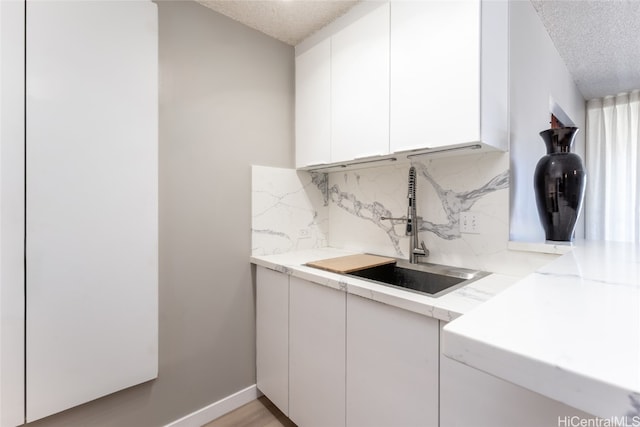 washroom with sink, a textured ceiling, and light wood-type flooring