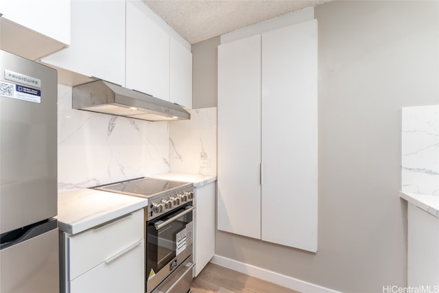 kitchen featuring appliances with stainless steel finishes, white cabinets, light wood-type flooring, and backsplash