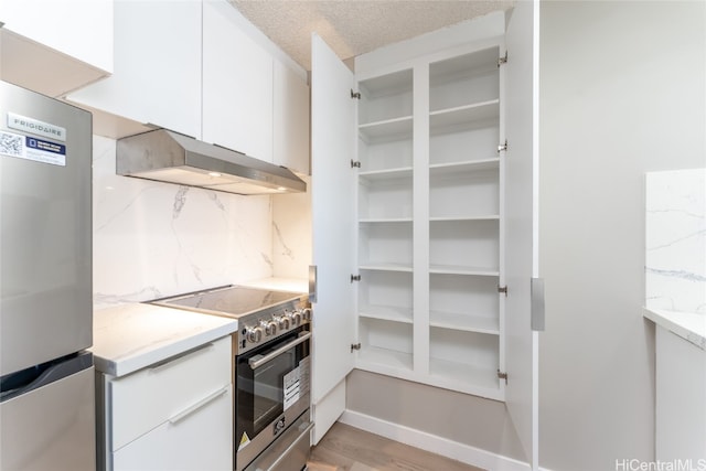 kitchen featuring light hardwood / wood-style floors, stainless steel appliances, light stone countertops, and white cabinets