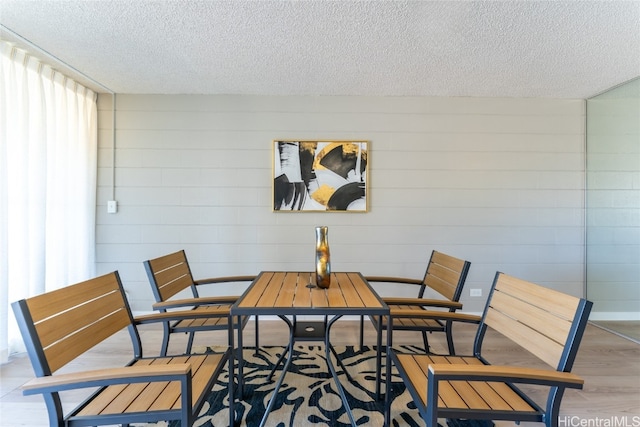 dining area with a textured ceiling and light hardwood / wood-style floors