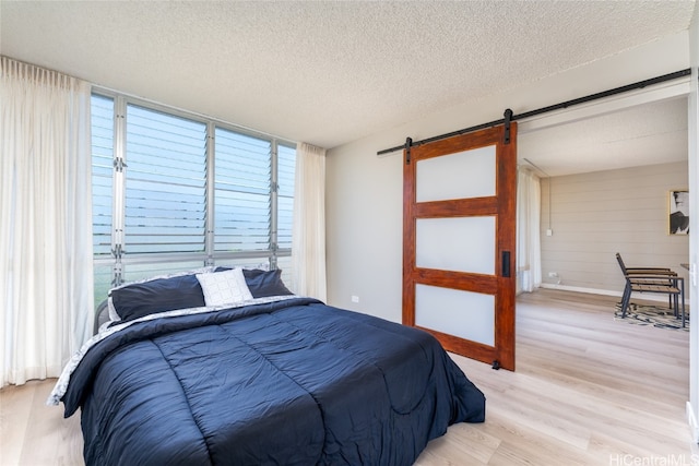 bedroom featuring wood walls, a textured ceiling, and light wood-type flooring