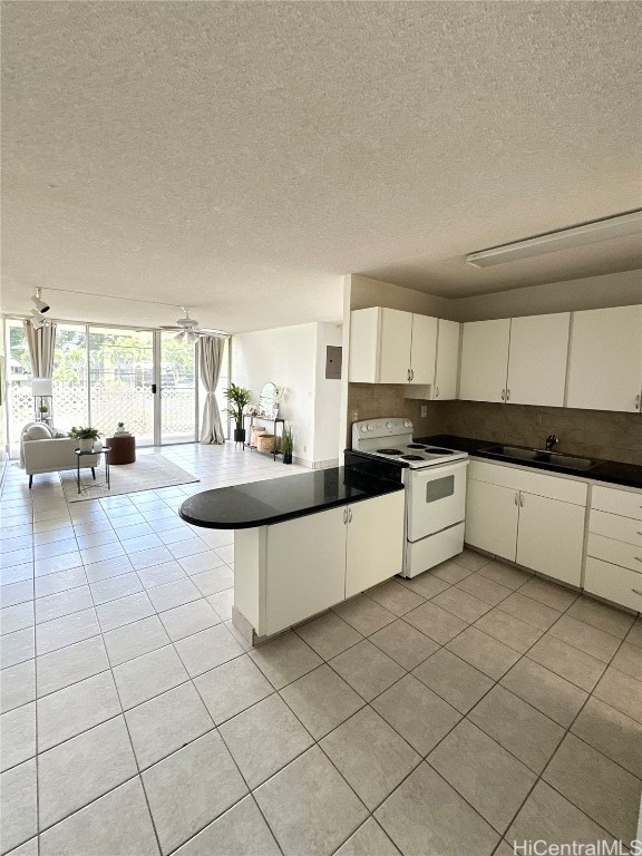 kitchen with white cabinets, kitchen peninsula, a textured ceiling, and electric stove