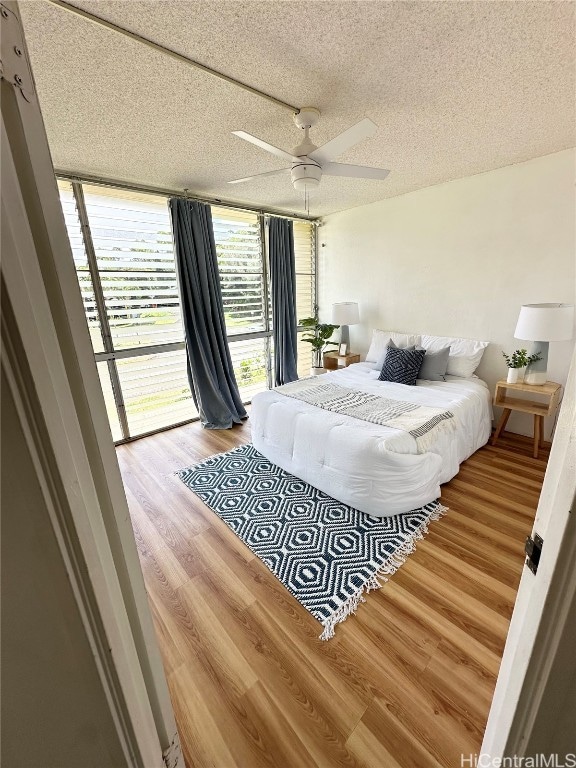 bedroom with ceiling fan, hardwood / wood-style flooring, a textured ceiling, and access to exterior