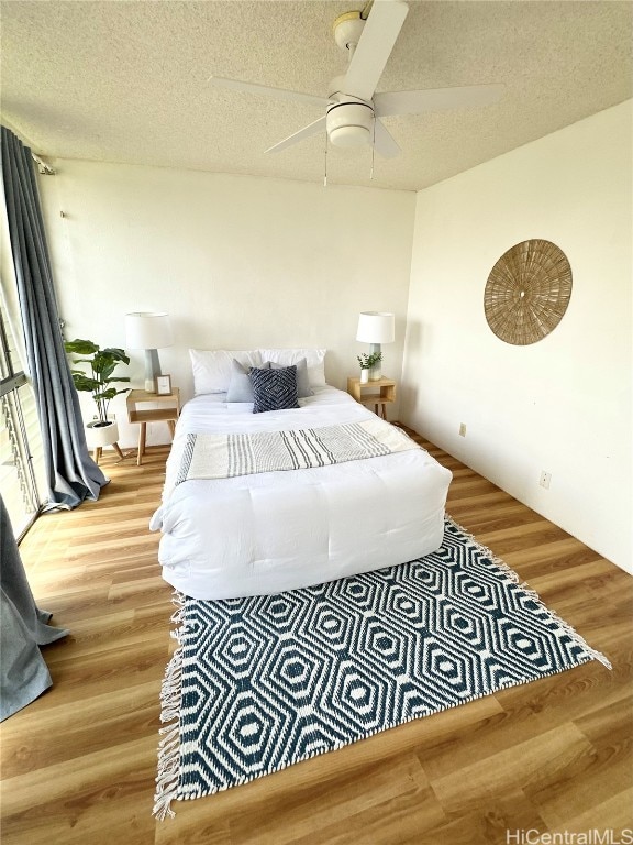 bedroom with hardwood / wood-style floors, a textured ceiling, and ceiling fan