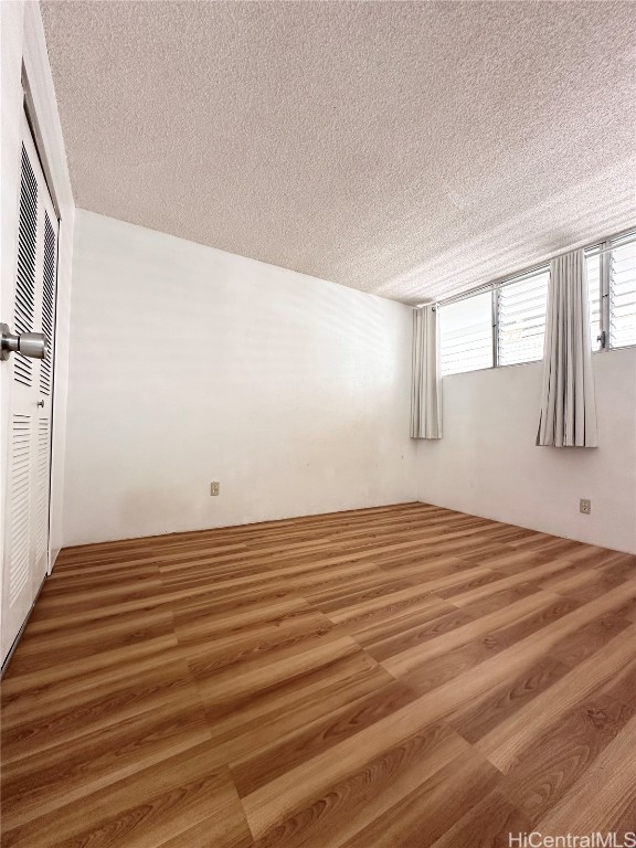 spare room with a textured ceiling and wood-type flooring