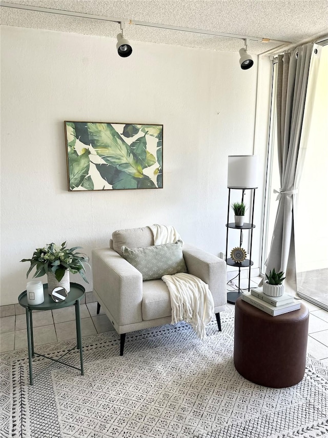 living area with tile patterned floors, a textured ceiling, and track lighting