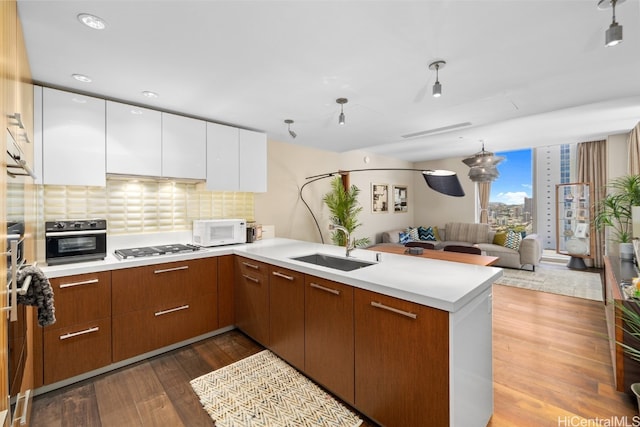 kitchen with white cabinetry, kitchen peninsula, wood-type flooring, and oven