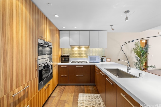 kitchen featuring white cabinets, light hardwood / wood-style flooring, gas cooktop, double oven, and sink