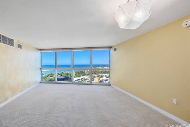 carpeted spare room with a wall of windows and a water view