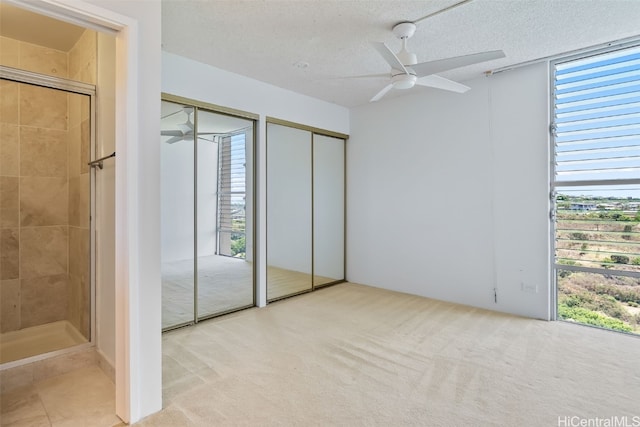 unfurnished bedroom with light carpet, multiple windows, and a textured ceiling