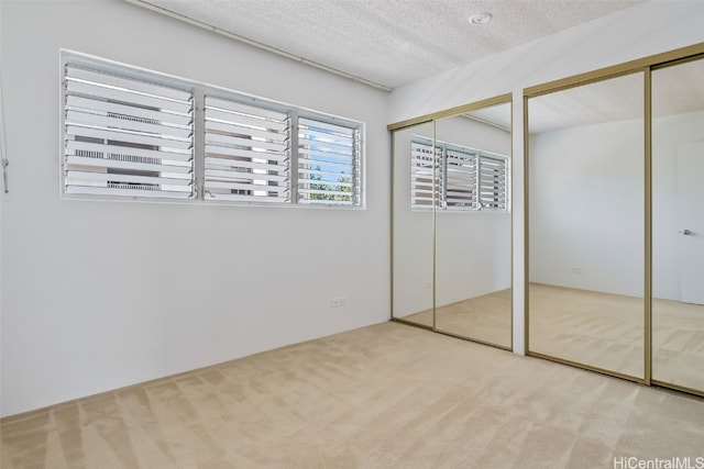 unfurnished bedroom with two closets, light carpet, and a textured ceiling