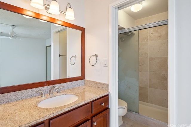 bathroom with vanity, toilet, a shower with shower door, and ceiling fan