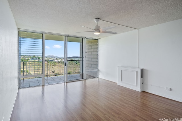 empty room with ceiling fan, hardwood / wood-style flooring, and a textured ceiling