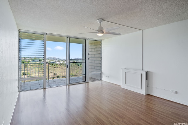 98-707 Iho Pl Unit 2-1404, Aiea, HI 96701 - empty room featuring a wall of windows, wood finished floors, a textured ceiling, ceiling fan, and a mountain view
