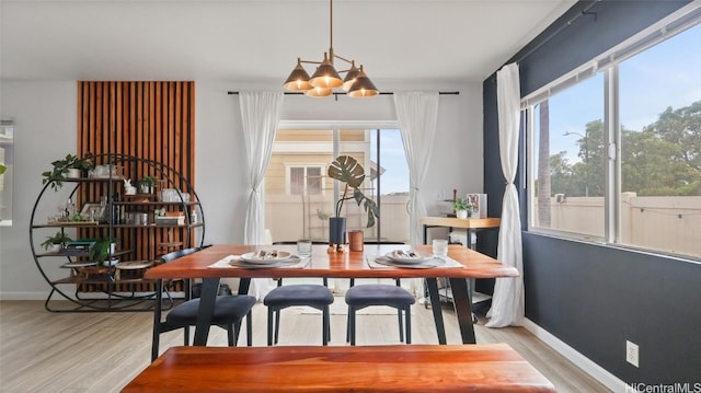 dining space featuring plenty of natural light, light hardwood / wood-style floors, and an inviting chandelier