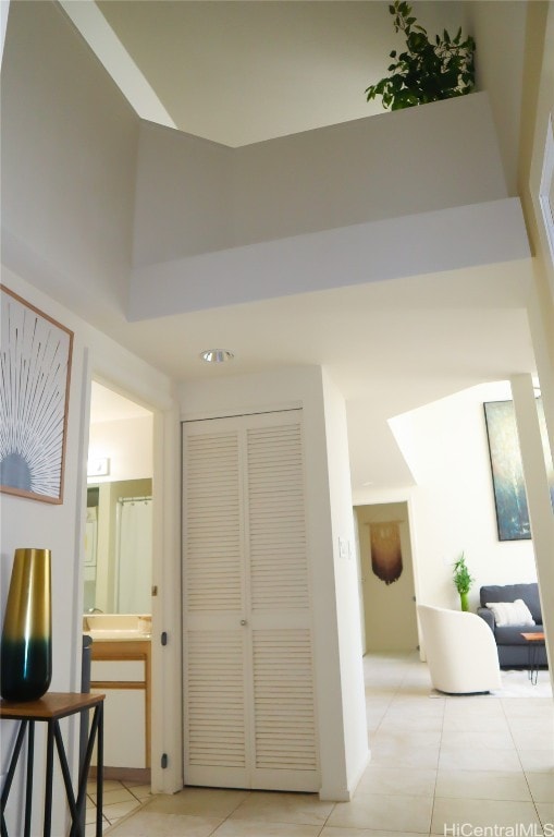 hallway with light tile patterned flooring and a high ceiling